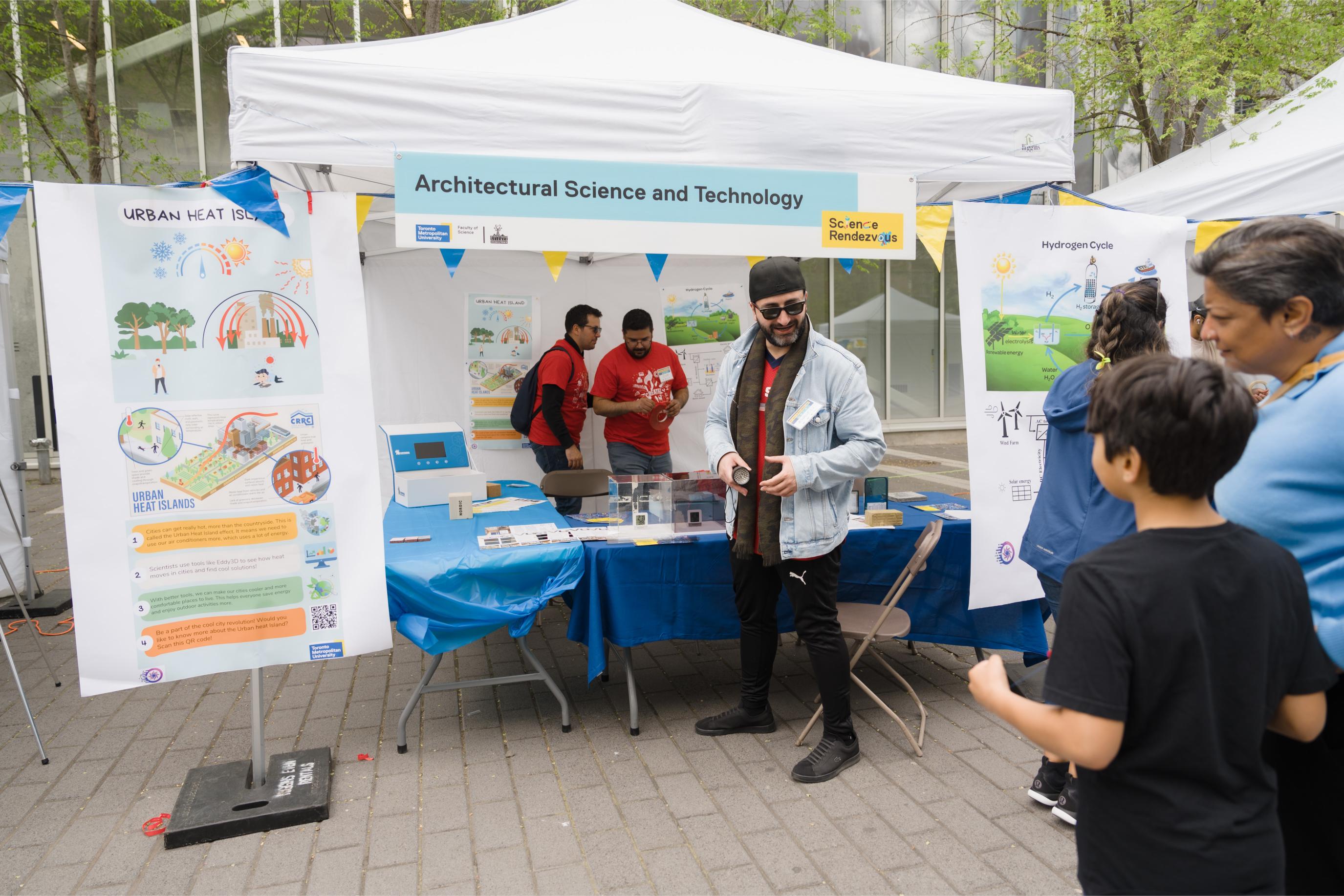 Volunteers engaging with participants at the Architectural Science and Technology Booth.